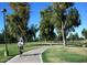 Scenic bike path winding through a lush green park with mature trees and a clear blue sky at 1211 N Miller Rd # 213, Scottsdale, AZ 85257