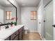 Bathroom featuring a framed mirror, vanity with sink, window, toilet, and walk-in shower with glass doors at 12427 W El Nido Ln, Litchfield Park, AZ 85340