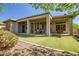 Wide backyard features covered patio, dining set, ample green lawn, and beautiful landscaping, a true outdoor retreat at 1557 W Laurel Greens Ct, Anthem, AZ 85086