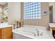 Bathroom featuring a soaking tub, glass block window, vanity and tiled floors at 1557 W Laurel Greens Ct, Anthem, AZ 85086