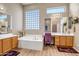 A luxurious bathroom featuring a soaking tub, dual sinks, and plenty of natural light from the window at 1557 W Laurel Greens Ct, Anthem, AZ 85086