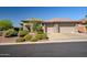 Well-manicured front yard showcasing desert landscaping, a three-car garage and neutral tones at 1557 W Laurel Greens Ct, Anthem, AZ 85086