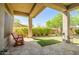 Covered patio showing stone flooring, decorative bench, and a meticulously maintained backyard with green grass at 1557 W Laurel Greens Ct, Anthem, AZ 85086