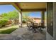 Inviting covered patio features stone flooring and an outdoor dining set overlooking the well-manicured backyard at 1557 W Laurel Greens Ct, Anthem, AZ 85086
