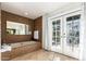 Bright bathroom features a stylish tub with mosaic tile, a large mirror, and access to the outdoors through double doors at 17012 N 57Th St, Scottsdale, AZ 85254