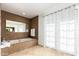 Elegant bathroom featuring a mosaic-tiled tub, a large mirror, and natural light streaming through the window at 17012 N 57Th St, Scottsdale, AZ 85254