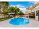 Beautiful pool features clear blue water, rock detail, and manicured lawn with an umbrella under a partly cloudy sky at 17012 N 57Th St, Scottsdale, AZ 85254