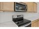 Close-up of stainless steel microwave and electric stove with white backsplash and light wood cabinets at 17643 W Rancho Dr, Litchfield Park, AZ 85340