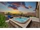 Inviting backyard hot tub and patio featuring an outdoor table set, seating area, and beautiful sunset views at 17913 W Sunward Dr, Goodyear, AZ 85338