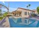 Backyard pool view surrounded by green landscaping and mature palm trees under a partly cloudy sky at 186 N Starboard Dr, Gilbert, AZ 85234
