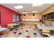 Activity room featuring tables, chairs, red accent wall and light wood cabinets at 20183 N Big Dipper Dr, Maricopa, AZ 85138
