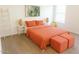 Bright bedroom featuring wood floors, white walls, a bed with orange quilt and matching ottoman, and simple decor at 22787 W Gardenia Dr, Buckeye, AZ 85326