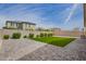 The backyard has a brick patio, artificial grass, and gravel leading to a wall with bushes separating it from neighbors at 23020 E Excelsior Ave, Queen Creek, AZ 85142