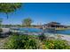 Picturesque view of a pond with lush greenery, a community building, and a walking path at 23020 E Excelsior Ave, Queen Creek, AZ 85142