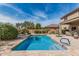 Backyard oasis featuring a sparkling pool, lush landscaping, and a covered patio for ultimate relaxation at 26011 W Tonopah Dr, Buckeye, AZ 85396