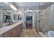 Bathroom with dual sinks, a glass shower, soaking tub, and an entrance to a walk-in closet at 27173 N 86Th Ave, Peoria, AZ 85383