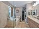 Bathroom featuring a soaking tub, walk-in shower with glass block, and dual sinks at 27173 N 86Th Ave, Peoria, AZ 85383