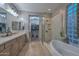 Bathroom featuring a soaking tub, glass enclosed shower, and double sink vanity at 27173 N 86Th Ave, Peoria, AZ 85383