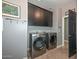 Well-lit laundry room featuring stainless steel washer and dryer and dark cabinets at 27173 N 86Th Ave, Peoria, AZ 85383