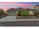 Charming single-story home featuring a well-manicured front yard and attached two-car garage during sunset at 31096 N 133Rd Ave, Peoria, AZ 85383