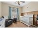 Cozy Bedroom featuring a white crib, gray glider, blue curtains and a modern ceiling fan at 5320 W Fawn Dr, Laveen, AZ 85339