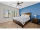 Cozy primary bedroom with a large bed, wood furniture, blue accent wall, and natural light at 5320 W Fawn Dr, Laveen, AZ 85339