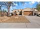 Tan home showcasing a well-manicured yard and front entrance on a sunny day with blue skies and a two car garage at 5320 W Fawn Dr, Laveen, AZ 85339