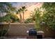 Cozy backyard featuring a brick wall, built-in grill, and lush palm trees at sunset at 7412 S Elm St, Tempe, AZ 85283