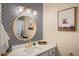 Stylish bathroom with designer wallpaper, modern mirror, and white vanity with gold accents at 7412 S Elm St, Tempe, AZ 85283