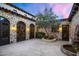 Charming courtyard with stone walls, arched doorways, and a beautiful tree feature, creating a private outdoor oasis at 8601 N 59Th Pl, Paradise Valley, AZ 85253