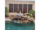 A close up of the waterfall feature by the pool and an Asian-themed garden. Creating a tranquil and serene outdoor space at 9908 E Medina Ave, Mesa, AZ 85209