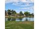Scenic pond on a golf course lined with trees and green grass under a bright, partly cloudy sky at 9908 E Medina Ave, Mesa, AZ 85209