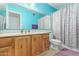 Light blue bathroom featuring wood vanity, large mirror, and patterned shower curtain at 1114 W Meseto Ave, Mesa, AZ 85210