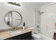 Well-lit bathroom featuring a granite countertop, a round mirror, and a shower-tub combination at 11925 N 67Th Dr, Peoria, AZ 85345
