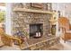 Close-up of a stone fireplace with decorative mantle, candles, and wicker chair in an inviting living space at 12749 E Poinsettia Dr, Scottsdale, AZ 85259