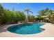 Beautiful pool and spa area with a rock waterfall, surrounded by mature landscaping and palm trees at 12749 E Poinsettia Dr, Scottsdale, AZ 85259