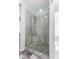 Modern walk-in shower featuring neutral stone tile, pebble floor, glass door, and bench at 1425 E Darrel Rd, Phoenix, AZ 85042