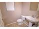 Cozy powder room with tiled floors, a white pedestal sink, and a toilet adjacent to a bright window at 1524 N Milly Pl, Casa Grande, AZ 85122