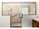 Modern bathroom featuring a glass-enclosed shower with stone tile and a shower head at 15656 W Devonshire Ave, Goodyear, AZ 85395