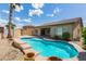 Backyard pool features a baja step entry, mature landscaping and views of the surrounding neighborhood at 15656 W Devonshire Ave, Goodyear, AZ 85395