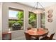 Bright dining area with a round table, and natural light streaming through expansive windows overlooking lush greenery at 16151 W Fairmount Ave, Goodyear, AZ 85395
