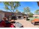 Inviting backyard features an outdoor fireplace, grill, and well-manicured artificial lawn at 16511 W Cortez St, Surprise, AZ 85388