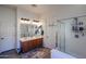 Bathroom featuring double sinks with wood cabinets, an enclosed shower, and wood-look flooring at 16511 W Cortez St, Surprise, AZ 85388