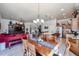 Open floor plan with kitchen, dining area, and living room with red sofa and wooden entertainment center at 16511 W Cortez St, Surprise, AZ 85388