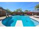 A backyard pool with a slide and diving board, waterfall features, and jacuzzi is ready for fun and relaxation in the sun at 16511 W Cortez St, Surprise, AZ 85388
