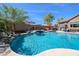 Backyard pool with a waterfall feature and jacuzzi surrounded by a patio, with plenty of seating under colorful umbrellas at 16511 W Cortez St, Surprise, AZ 85388