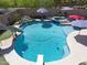 Beautiful backyard pool with a rock waterfall, spa, slide, and diving board, surrounded by lush greenery at 16511 W Cortez St, Surprise, AZ 85388