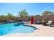 Backyard pool featuring a rock waterfall, jacuzzi, lush seating area, and tropical landscaping at 16511 W Cortez St, Surprise, AZ 85388