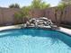 Relaxing pool with a rock waterfall feature and lush landscaping, perfect for a tranquil backyard retreat at 16511 W Cortez St, Surprise, AZ 85388