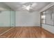 Bedroom showcasing hardwood flooring, a mirrored wall, and a large window for natural light at 18211 N Conestoga Dr, Sun City, AZ 85373